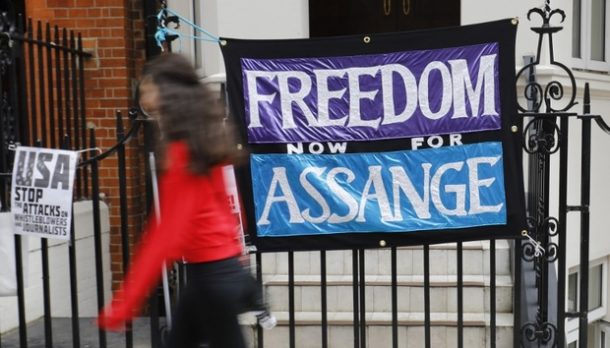 A pedestrian passes a banner reading ‘Freedom for Assange’ outside the Ecuadorian embassy on 30 July 2018 (Photo: AFP)