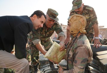 Syrian President Bashar Al-Assad greets a soldier on a tank in the town of Al-Hobeit in southern Idlib.