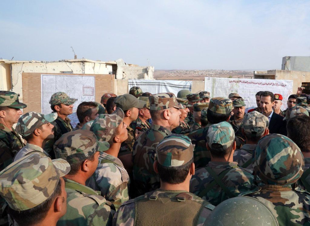 Syrian President Bashar Al-Assad is greeted by several soldiers in the town of Al-Hobeit.
